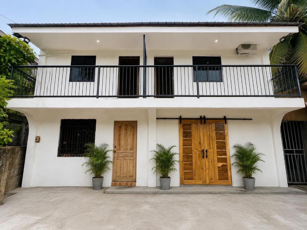 a white house with two doors and a balcony at The LineUp Surf House Pacifico in San Isidro