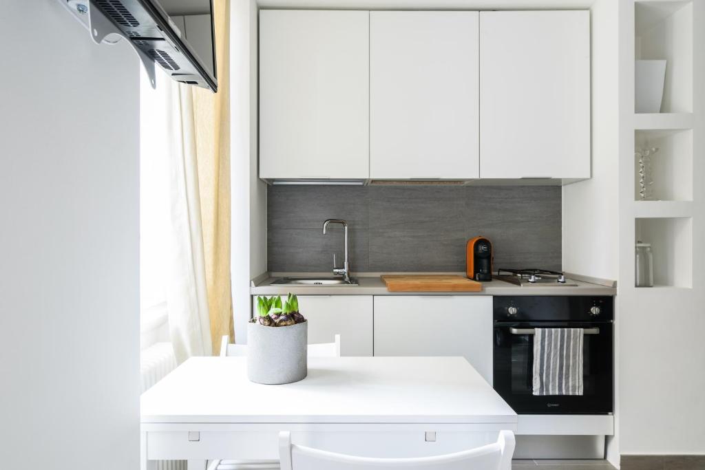 ミラノにあるCiaia Apartamentの白いキャビネットとシンク付きのキッチン