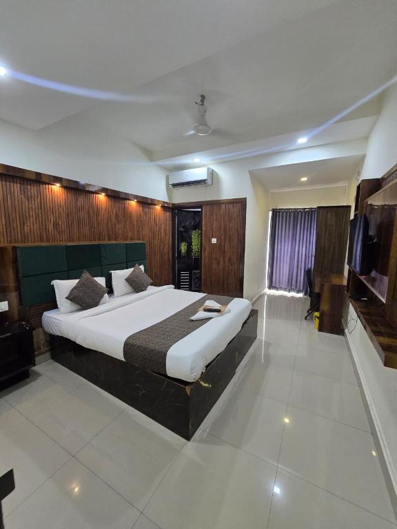 a bedroom with a large bed and a television at Queens Residency - Kochi in Cochin