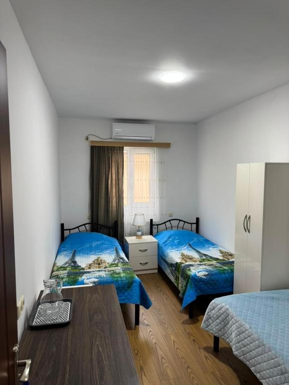 a room with two beds and a wooden table at NAPO HOTEL სასტუმრო ნაპო in Zugdidi