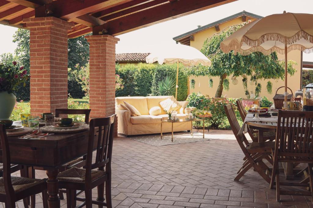 a patio with a couch and tables and chairs at Villa Anastasia in Carpi