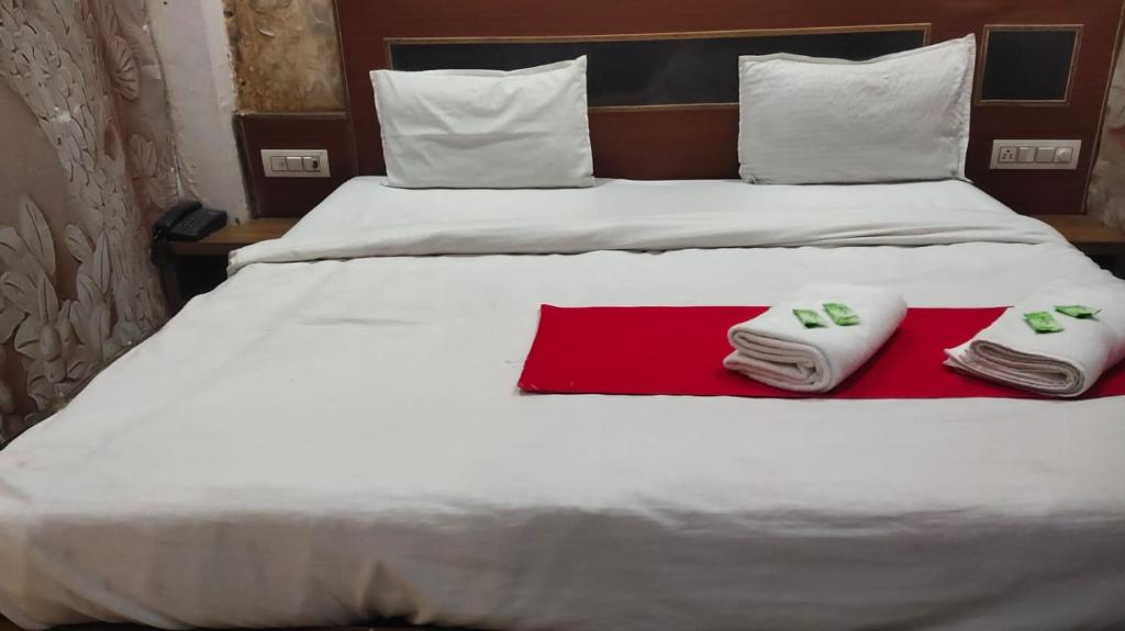 a bed with two towels sitting on top of it at Triveni Inn in Jahāngīrābād