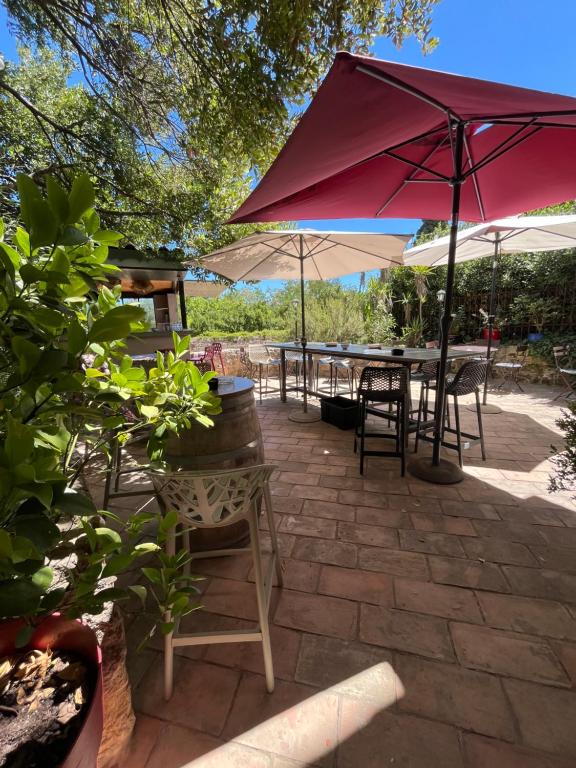 a patio with tables and umbrellas and chairs at Au bout du pré in Pézenas