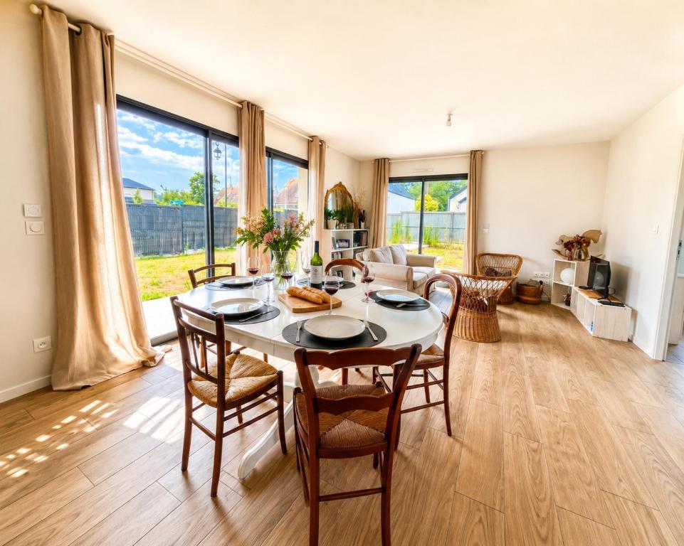 a dining room with a table and chairs and a living room at Le Clos de Luc - 3 chambres - Jardin - Plage à 5 min in Luc-sur-Mer