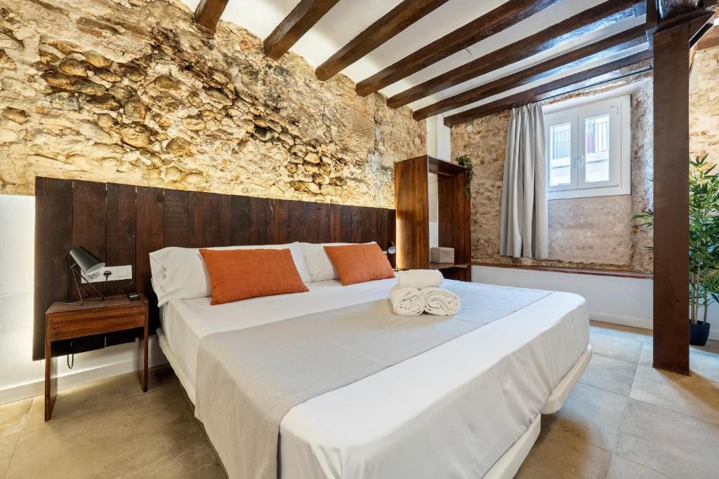 a bedroom with a large bed and a brick wall at Port Apartsuite in Tarragona