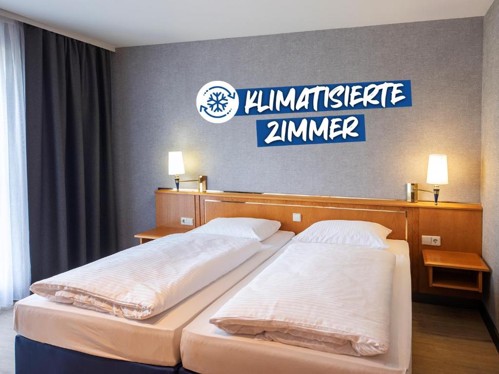 two beds in a hotel room with a sign on the wall at ACHAT Hotel Magdeburg in Magdeburg
