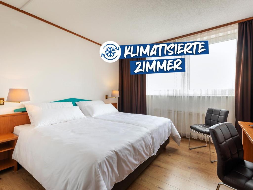 a hotel room with a large bed and a sign at ACHAT Hotel Frankfurt Maintal in Maintal