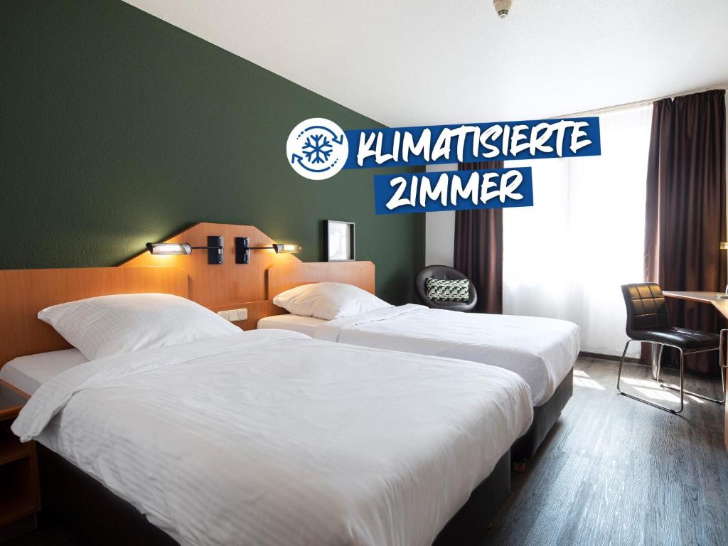 two beds in a hotel room with a sign on the wall at ACHAT Hotel Heppenheim in Heppenheim an der Bergstrasse