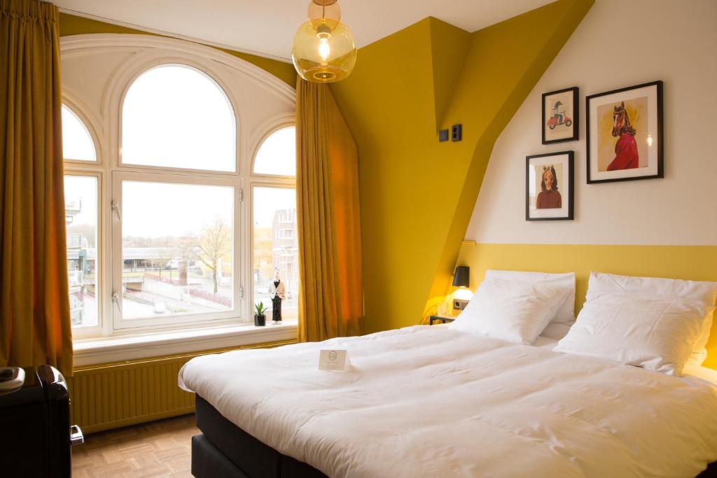 a bedroom with a large bed and a large window at Little Duke Hotel in Den Bosch