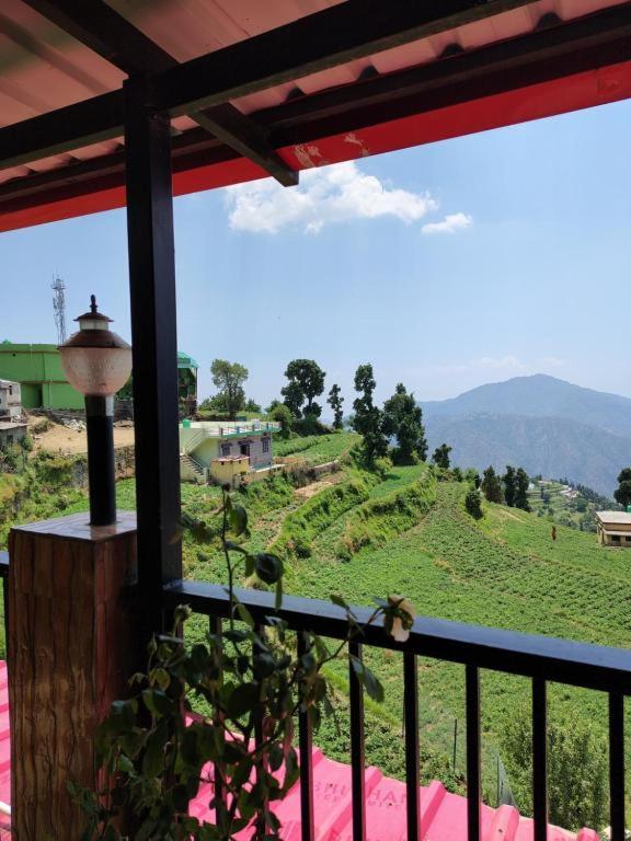 a balcony with a view of a green hill at Hotel Skyline in Kanatal