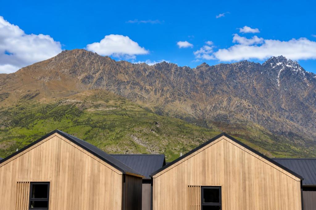 two wooden buildings with mountains in the background at Relax on Remarkable in Queenstown