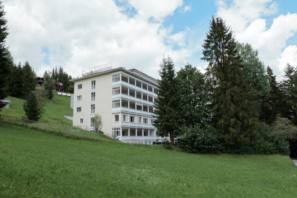 a white building on top of a green field at Davos Youth Hostel in Davos