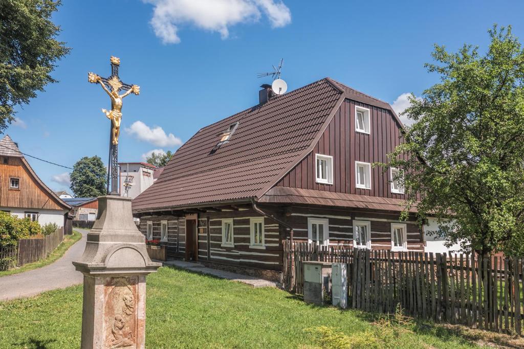 a large wooden house with a cross in front of it at Roubenka Kailas in Červená Voda