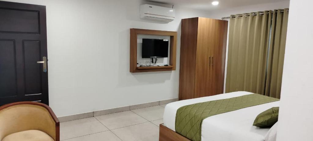 a bedroom with a bed and a tv on a wall at Anchani Residency Rooms in Pāmbādi