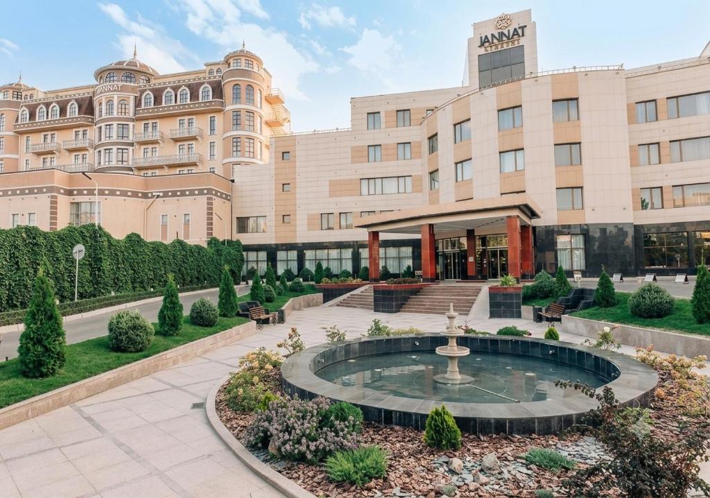 a hotel with a fountain in front of a building at Jannat Regency in Bishkek