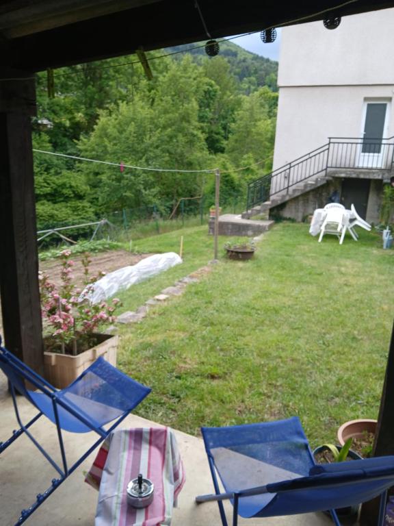 two blue chairs on a porch with a yard at bord de rivière in Accons