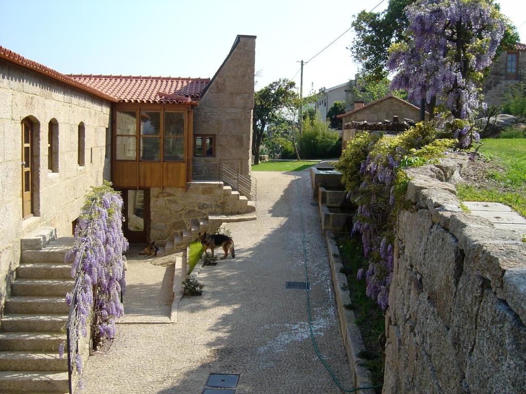 a house with a dog standing next to a wall at Quinta De Abol De Baixo in Entre-os-Rios