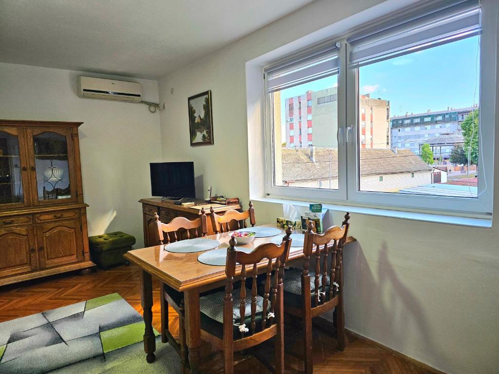 a dining room with a table and a large window at Centar Apartman in Apatin