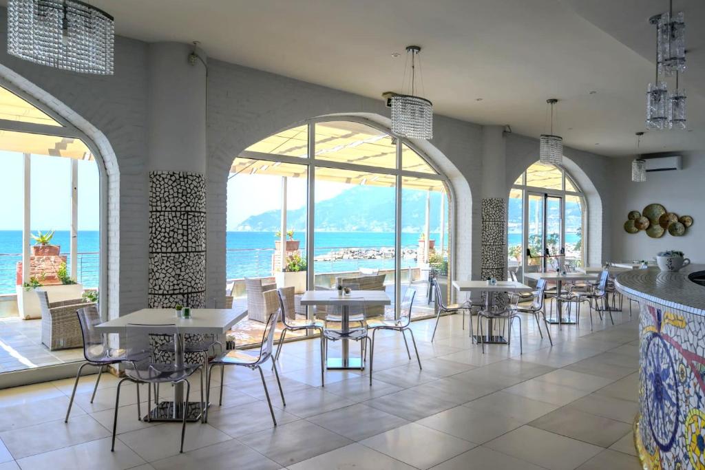 a restaurant with tables and chairs and a view of the ocean at Hotel Centro Congressi Polo Nautico in Salerno