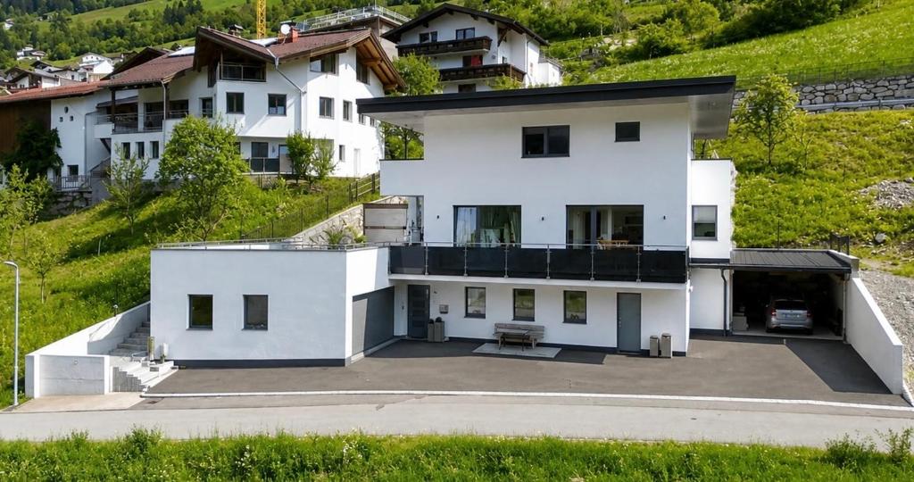 a white house on a hill with a parking lot at Apart Kathrin in Fliess