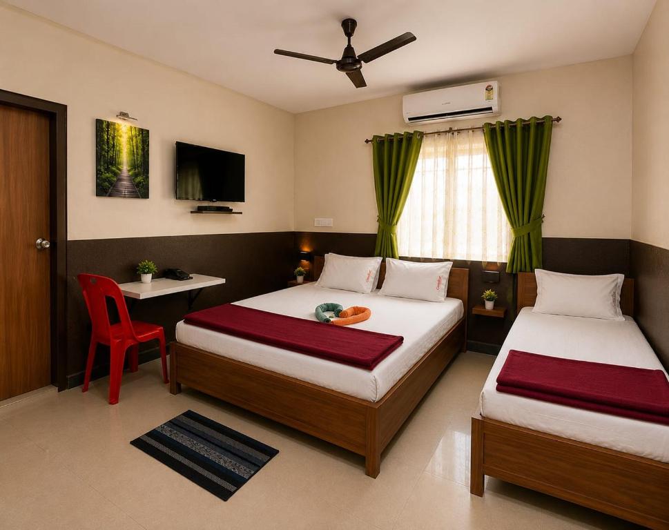 a bedroom with two beds and a table and a chair at Hotel Shepherds in Bīdar