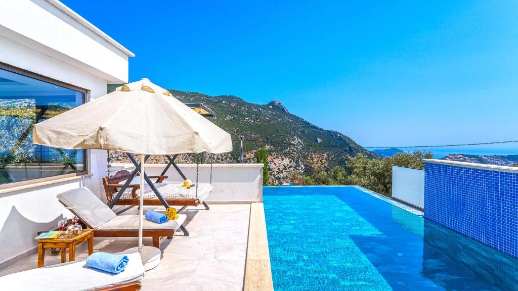 a villa with a swimming pool and an umbrella at Secluded Sea View Honeymoon Escape Jacuzzi Private Pool-Villa Bella1 Orkide in Üzümlü