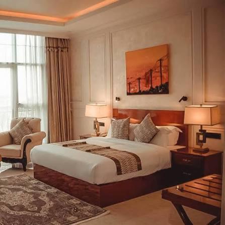 a hotel room with a bed and a chair at Galaxy La Palm Royal Hotel in Port Harcourt