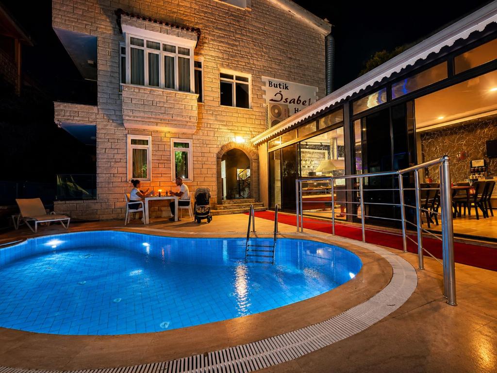 a swimming pool in front of a building at night at Butik İsabel Otel in Kemer