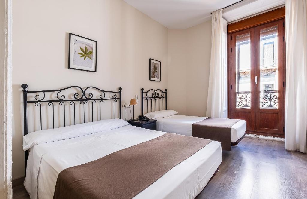 a bedroom with two beds and a window at Hostal El Pilar in Madrid