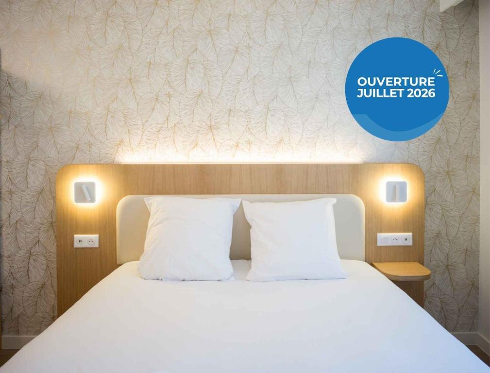 a bed with white pillows and a blue sign that says university bullet jobs at BRIT HOTEL CONFORT Roissy Saint-Witz in Saint-Witz