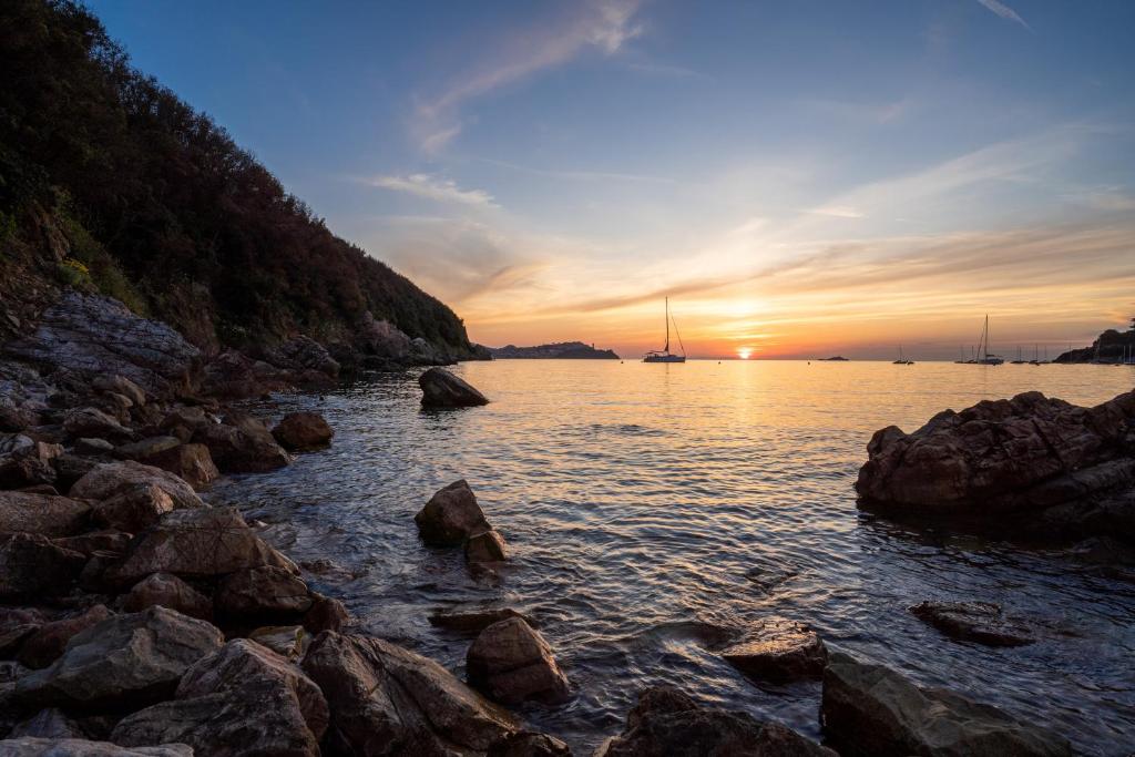 a sunset over a body of water with rocks at Elbitat Wellness&Spa in Bagnaia