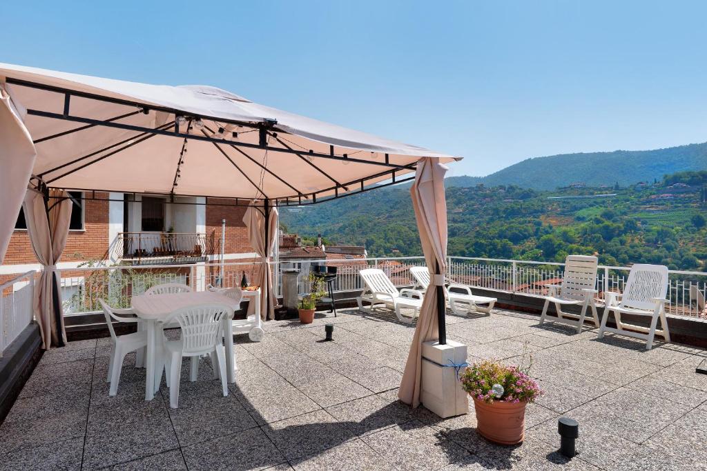 a patio with a table and chairs and an umbrella at Casa Rosetta - vicino Bordighera in Vallebona