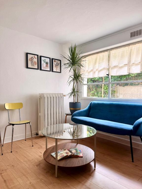 a living room with a blue couch and a table at Grand T2 neuf Chartrons in Bordeaux