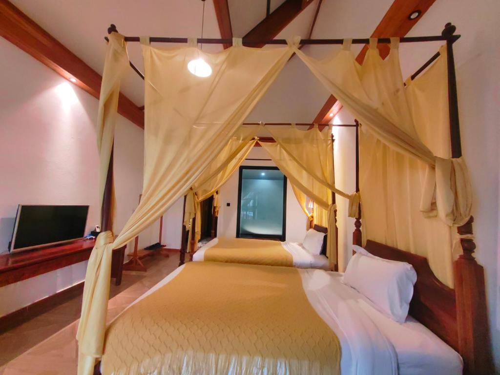 a bedroom with a canopy bed and a tv at Vangvieng Lina hotel in Vang Vieng