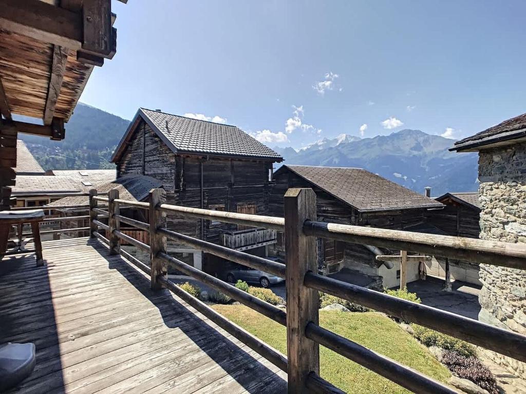 a wooden deck with a fence and mountains in the background at Laiterie 1 in Verbier