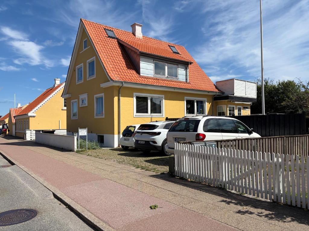 a yellow house with cars parked in front of it at Oddevej 20 Skagen in Skagen