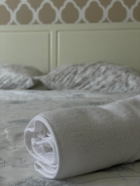 a white towel laying on top of a bed at Squarehouse Apartment Prishtina in Prishtinë