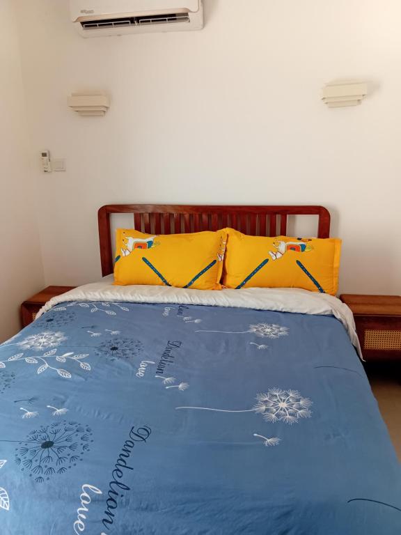 ein Bett mit blauer Bettdecke und gelben Kissen in der Unterkunft ZanziBeach Hotel in Jambiani