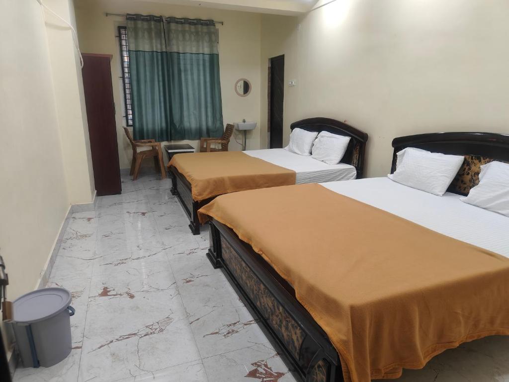 a hotel room with two beds and a table at Bheemas Grand Ps9 in Srikalahasti