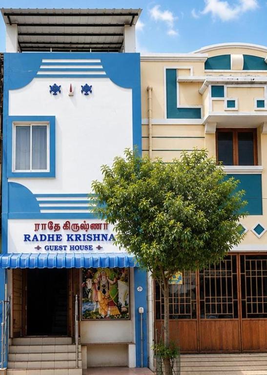 a blue and white building with a tree in front of it at Radhe Krishna Guest House in Srīrangam