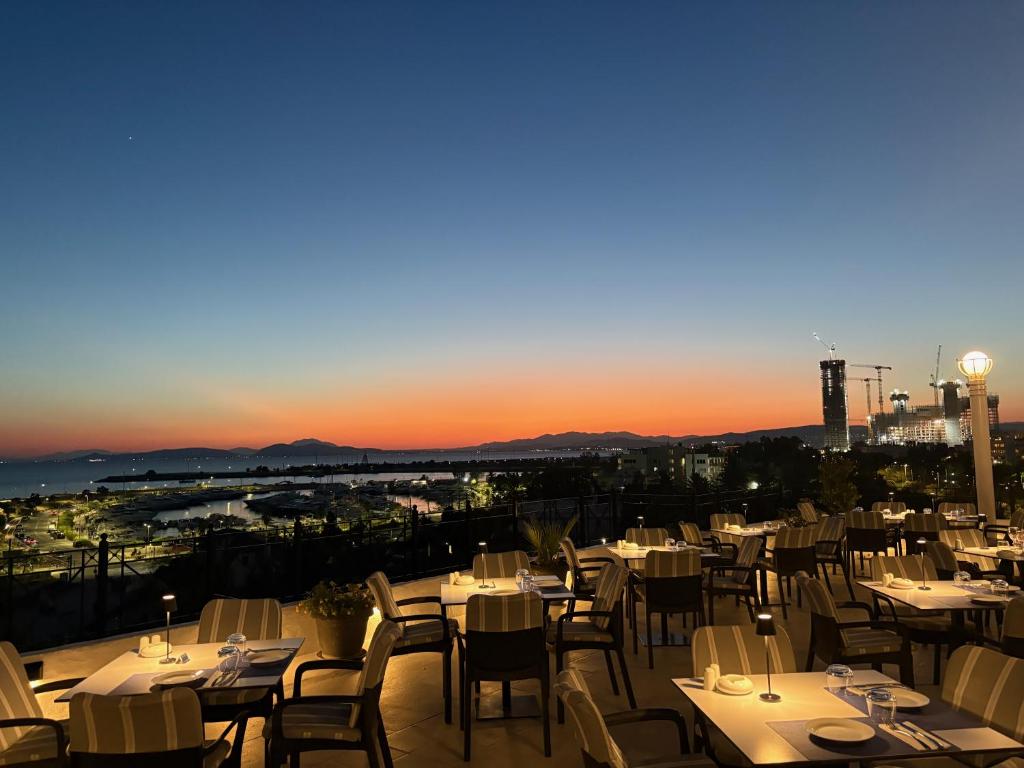 a restaurant with white tables and chairs and the sunset at Hotel London in Athens