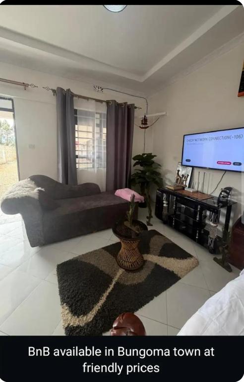a bedroom with a bed and a flat screen tv at NewNest in Bungoma