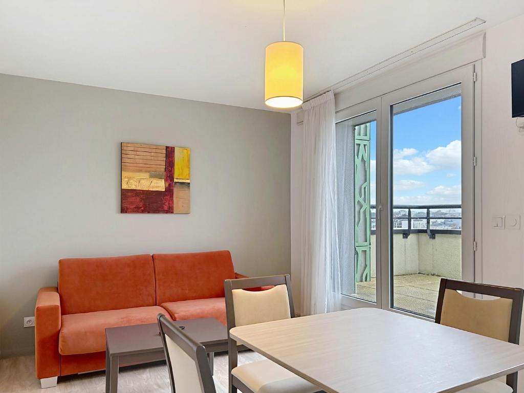 a living room with a couch and a table at Terres de France - Appart Hôtel Rouen Flaubert in Rouen