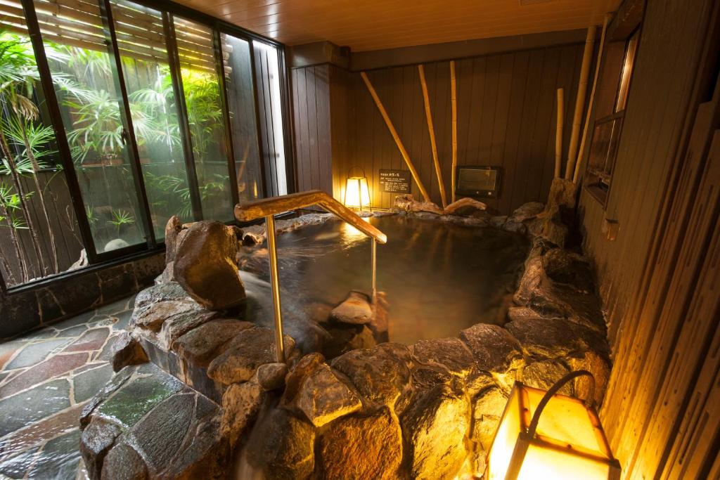 a hot tub in a room with a rock wall at Dormy Inn Hakata Gion in Fukuoka