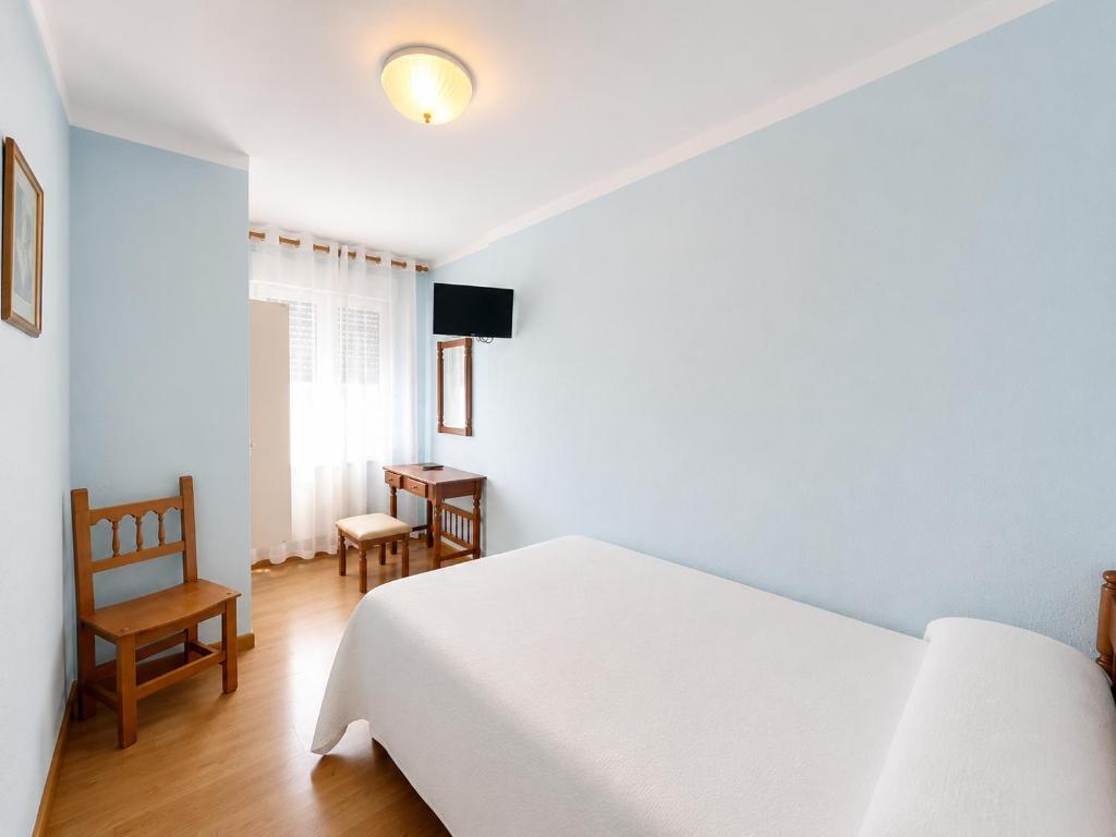 a bedroom with a white bed and a chair at Hostal ** EC León in León