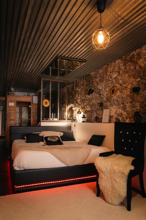 a bedroom with a large bed and a stone wall at Sweet Loft Grenoble-Love Room avec jacuzzi & sauna in Grenoble