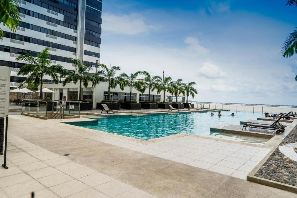 a swimming pool with palm trees and the ocean at Bellini 2 in Guayaquil
