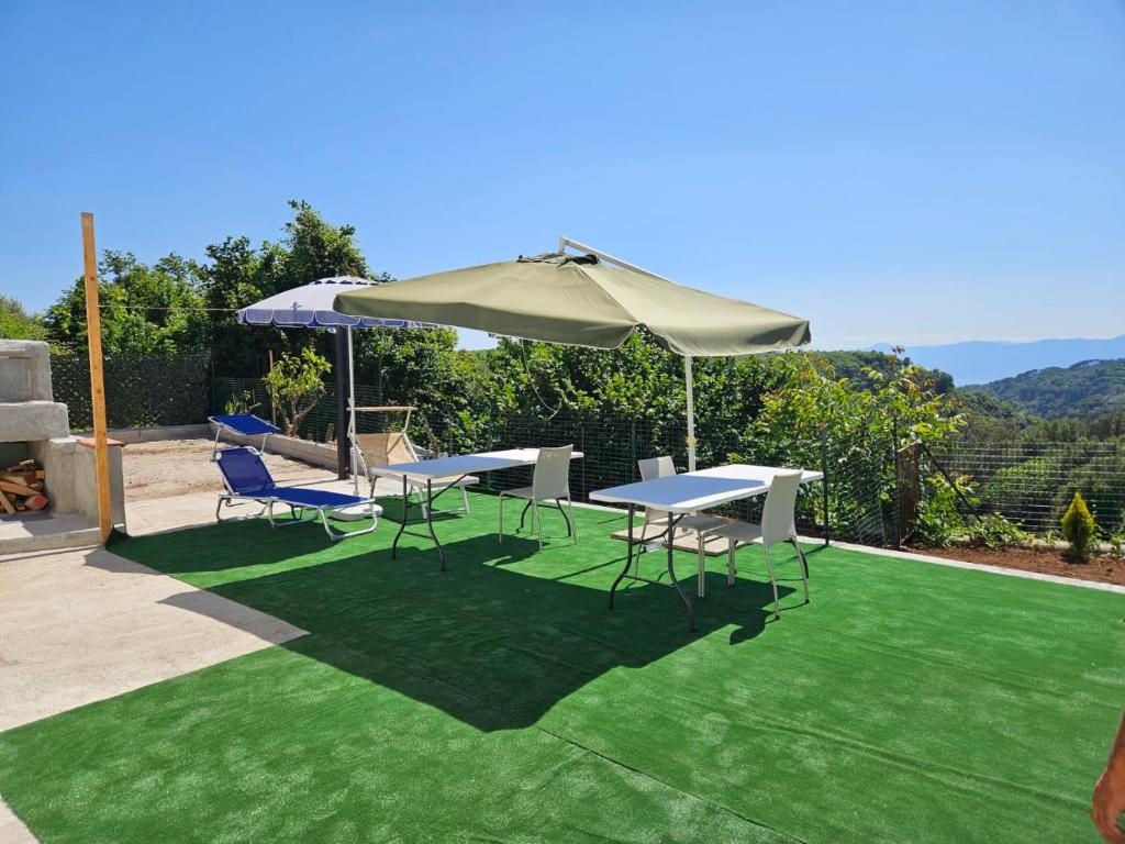 a table and chairs and an umbrella on a lawn at Villa Costa Viola in San Roberto