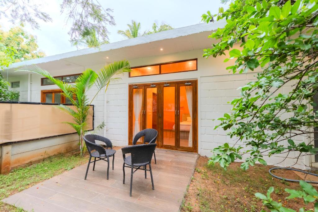a house with three chairs sitting on a patio at Aavaranaa Farmstay in Kanakapura
