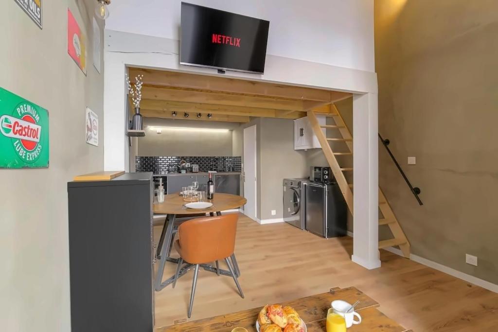 a living room with a table and a tv on a wall at Lyon Cité Internationale - Loft Industriel Neuf in Caluire-et-Cuire